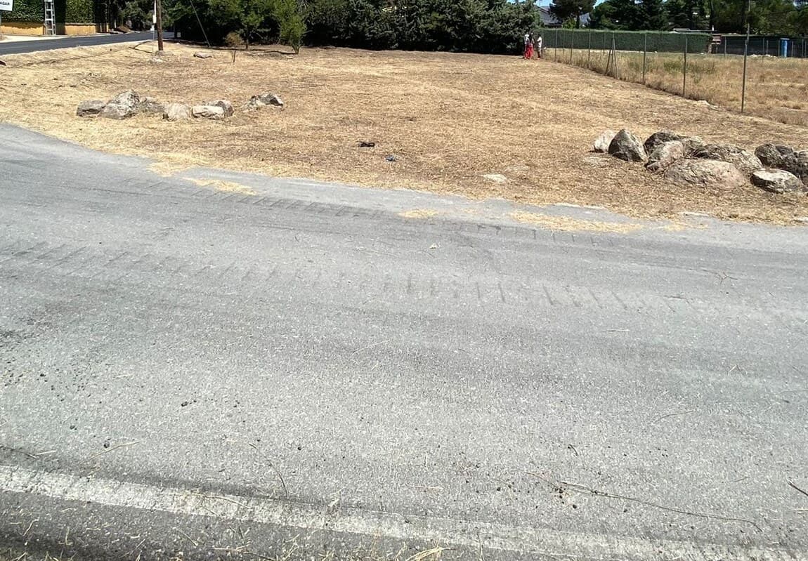 Parcela con afloramientos de granito en el borde, junto a un camino asfaltado